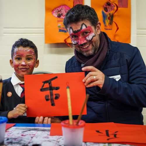 Man and boy holding Chinese calligraphy