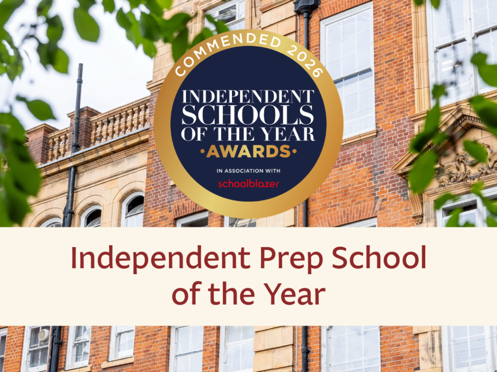 Brick school facade with a circular award badge reading 'Independent Schools of the Year' and green leaves in frame, foreground foliage visible.